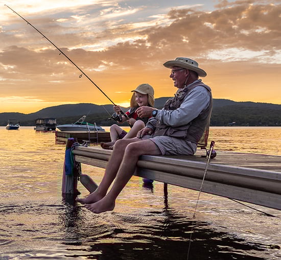 Grandfather and grandson fishing at sunset