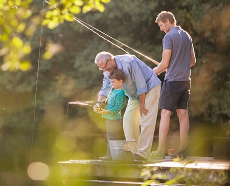 Boy, father and grandfather fishing in a lake
